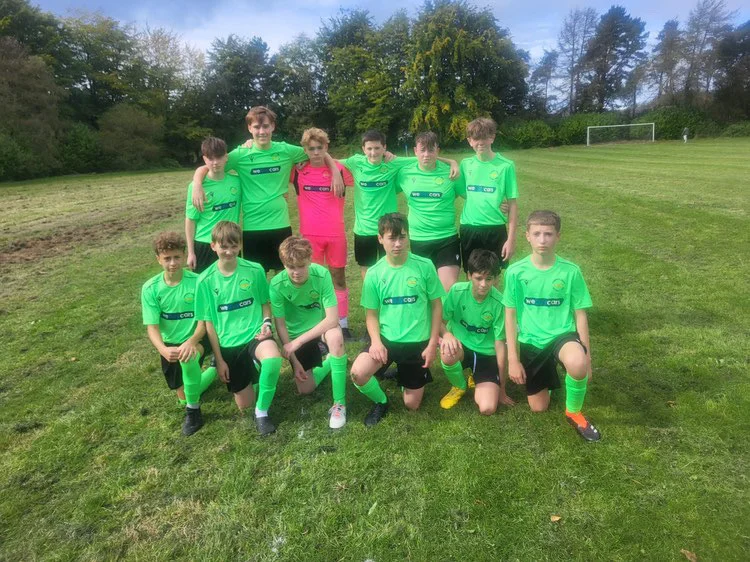 Corbridge United Juniors squad photo in the We Buy Cars Hexham bright green sponsored kit on the training pitch