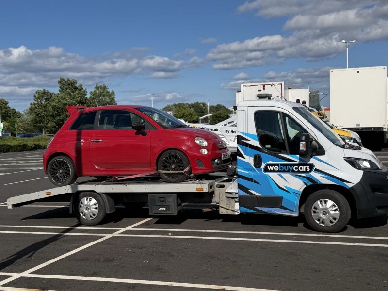 A red Fiat 500 Abarth loaded on the We Buy Cars Hexham flatbed recovery truck at Wark
